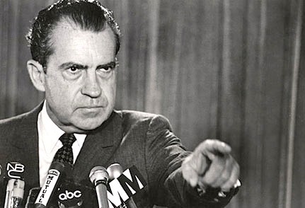 A black and white image of Richard Nixon at a press conference selecting a member of the press to ask a question about his opinion on marijuana, a substance which he hated.