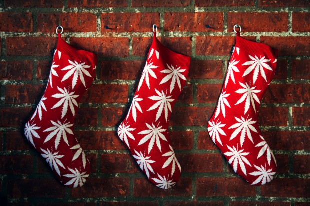Red Christmas stockings with white pot leaves hang on a brick mantel this holiday season.