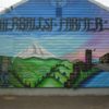 A mural on a CO dispensary building shows mountains lets passersby know that an "Herbalist Farmer" is there.