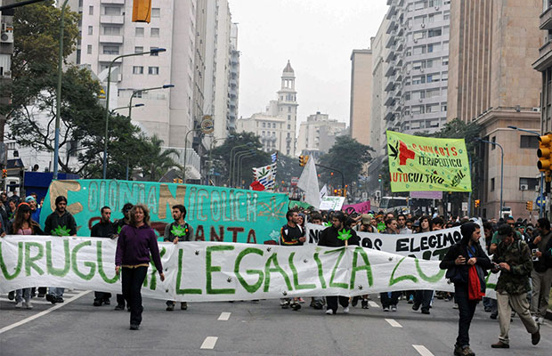 A rally of people parade down a Uruguayan road with signs calling for legalization of marijuana.