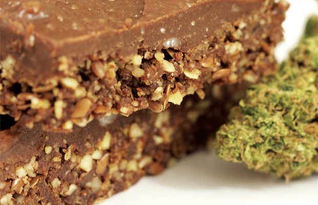 Crunchy brownies with a fudge topping sit next to a bud of marijuana.