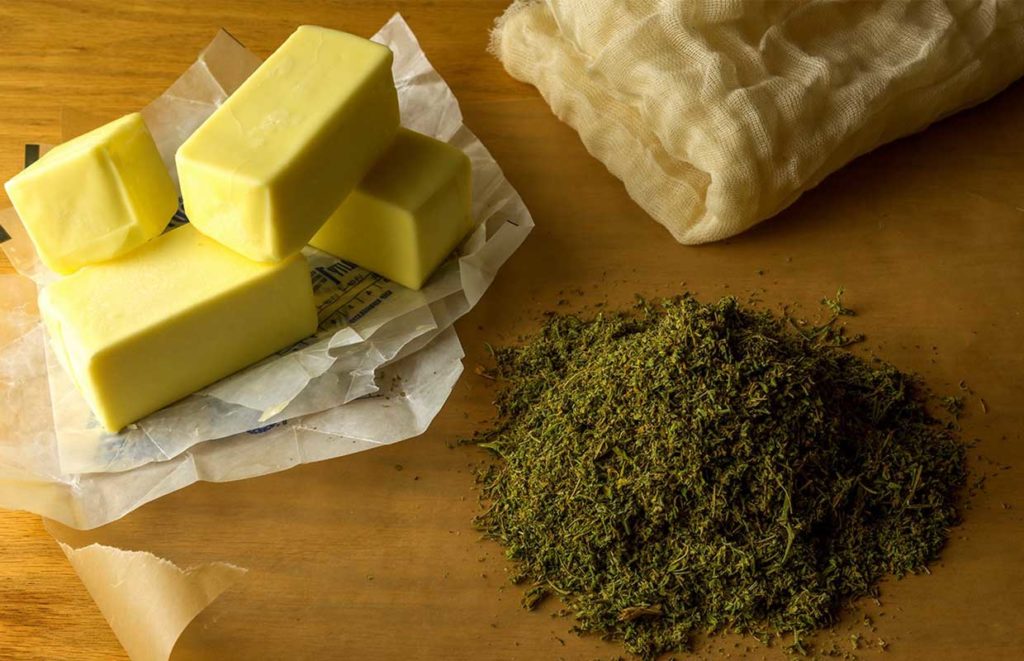 A cutting board holds butter, cheese cloth, and a pile of shake, someone is preparing to make homemade canna-oil and canna-butter.
