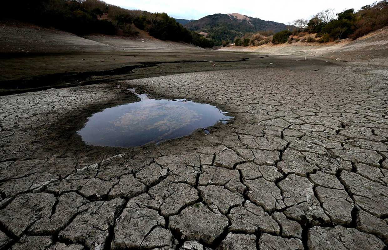 A desolate piece of land cracked from a drought, with a small puddle of water remaining. A drought like this in California could drive the prices of marijuana up.