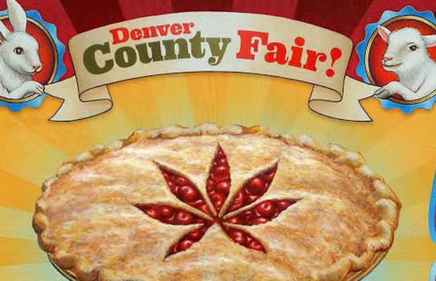 A sign with a cherry pie with a pot leaf cut out decoration. Above the pie the sign reads Denver Country Fair!