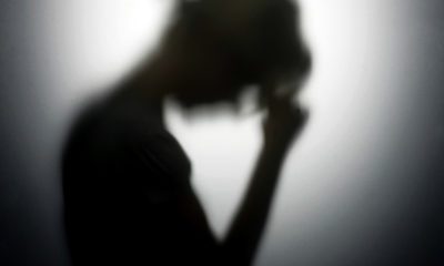 A silhouette of a woman holding her hand to her forehead to represent her anxiety, which can be treated with cannabis.