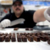 A chocolatier cuts squares of medicated chocolates at Cheeba Chews.