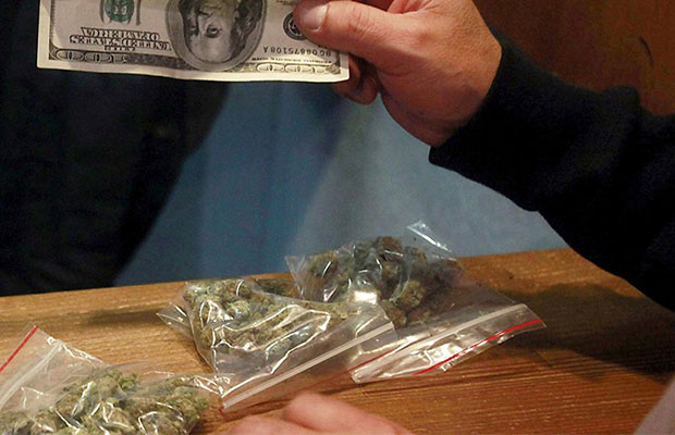 A man hands over a hundred dollar bill for bags of marijuana in Colorado.
