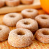 Infused vegan pumpkin spice donuts on and orange tiled rack