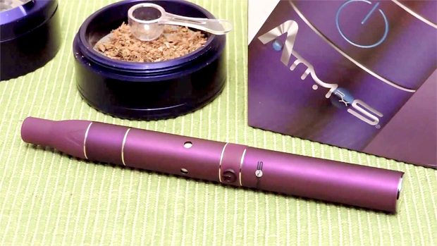 A purple wide view of the Atmos Raw next to a purple grinder full of cannabis.
