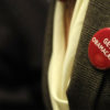 A man in a blazer sports a red pin that says "Get Obamacare" which does not cover medical marijuana.