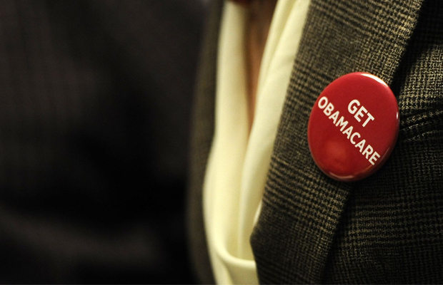A man in a blazer sports a red pin that says "Get Obamacare" which does not cover medical marijuana.