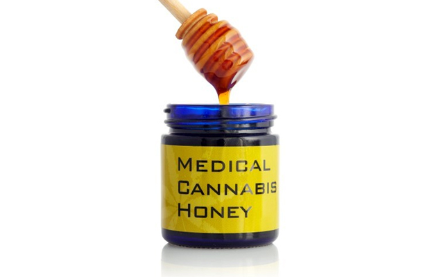 A jar of medical cannabis honey is pulled out by a dipper.