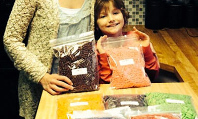 A young girl in need of medical marijuana poses with her mom as they hold bags of flavored CBD capsules.