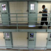 A guard walks along prison cells that contain marijuana offenders.