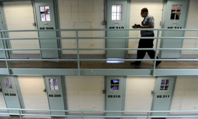 A guard walks along prison cells that contain marijuana offenders.