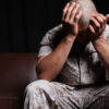 A veteran in camp holds his heads in his hands as he suffers an episode of PTSD, which now can be treated by MMJ in Michigan.