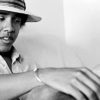 A black and white image of young Barack Obama in a fedora holds a joint in his hand.