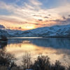 Beautiful sunset scene over a lake and snowy mountains.