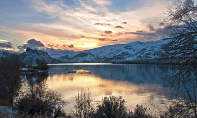 Beautiful sunset scene over a lake and snowy mountains.
