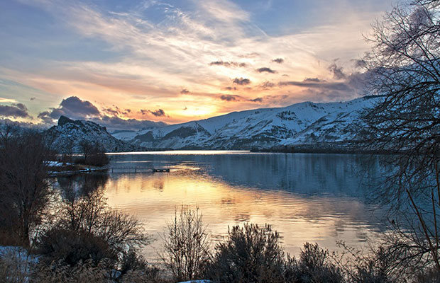 Beautiful sunset scene over a lake and snowy mountains.