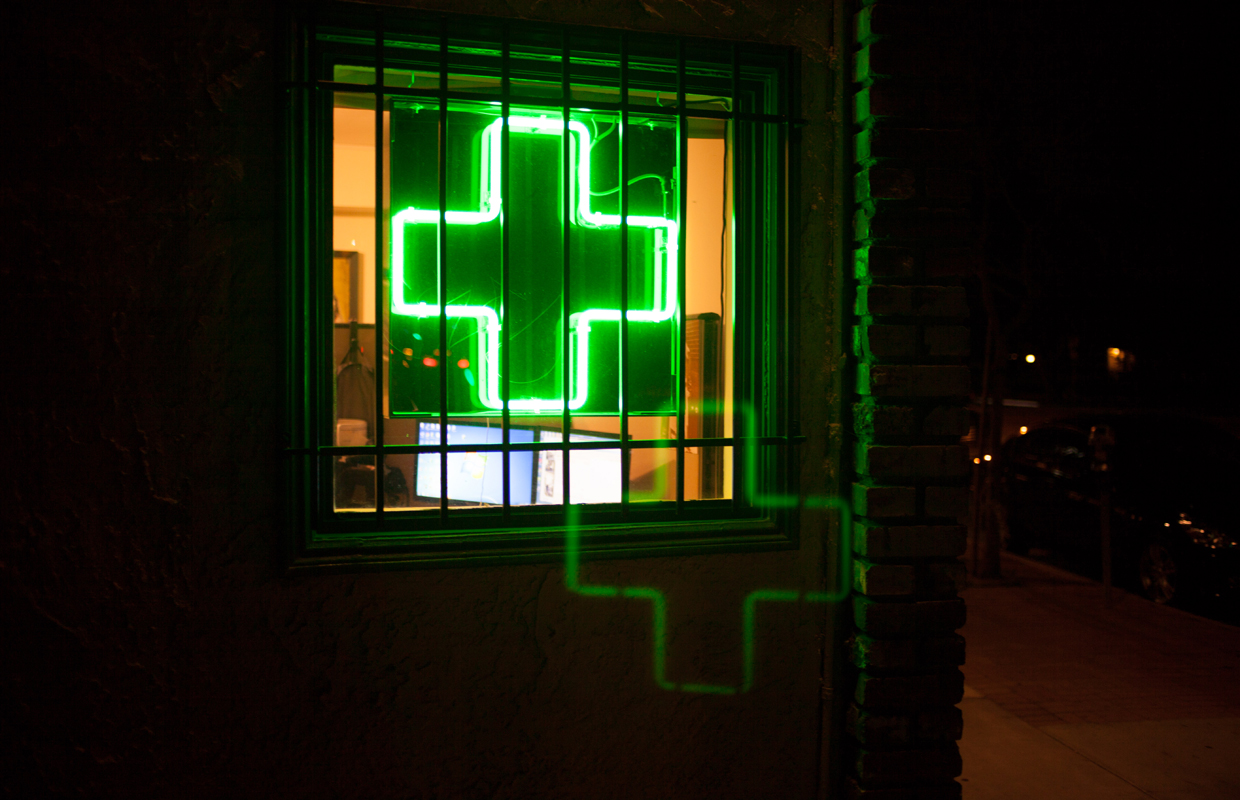Buds and Roses, a premier dispensary in So Cal, is closed for the day as a green medical cross shines through barred windows.