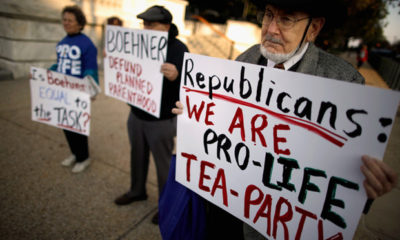 An older gentleman holds a sign saying "Republicans: We are pro-life tea party."