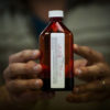 Hands hold out a prescription bottle full of liquid medication in South Carolina where medical marjiuana reform is on the way.