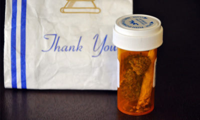 Prescription bottle in front of a "Thank You" prescription bag. In the bottle is a couple of nugs and a joint from a dispensary in Massachusetts