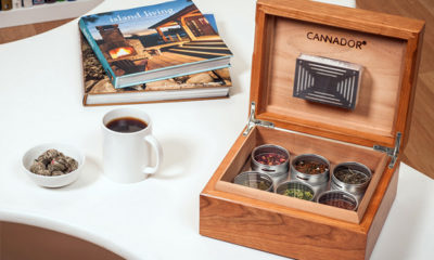 A Cannador box, a take on cigar humidors for cannabis, sites on a white table next to a cup of coffee and magazines.