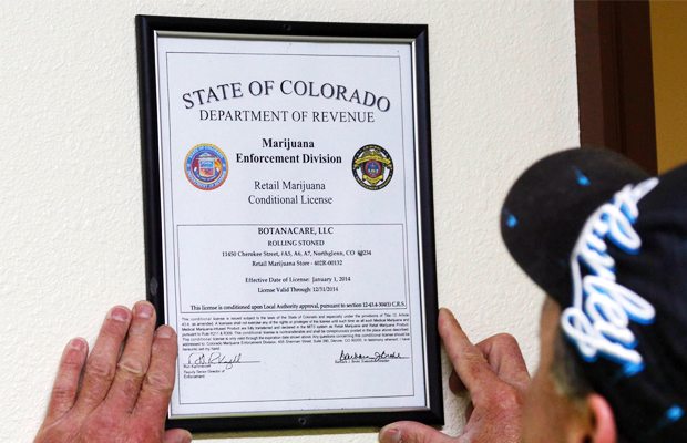 A man hangs his newly issued recreational marijuana business liscence in Colorado.