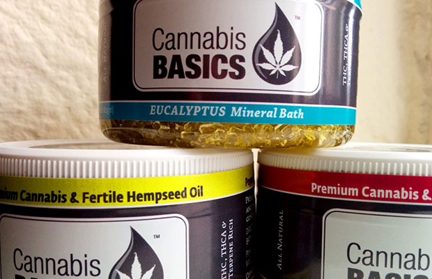 Three Cannabis Basic's jars filled with eucalyptus mineral bath salts and hempseed oil stack upon one another.