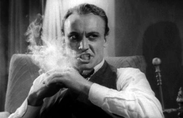 A black and white still from the 1930s movie "Reefer Madness" shows a man smoking marijuana and going insane.