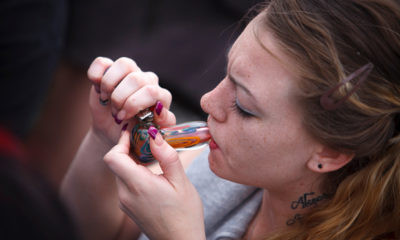 A woman takes a hit off of a bowl and prepares for the effects to settle in.