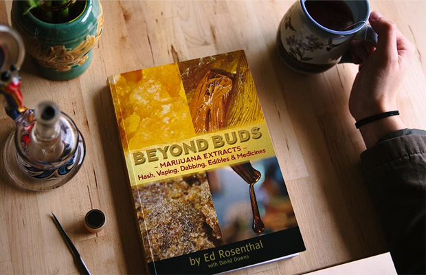Ed Rosenthal's "Beyond Buds" sits on a table with a cup of coffee, snacks, and a dab rig.