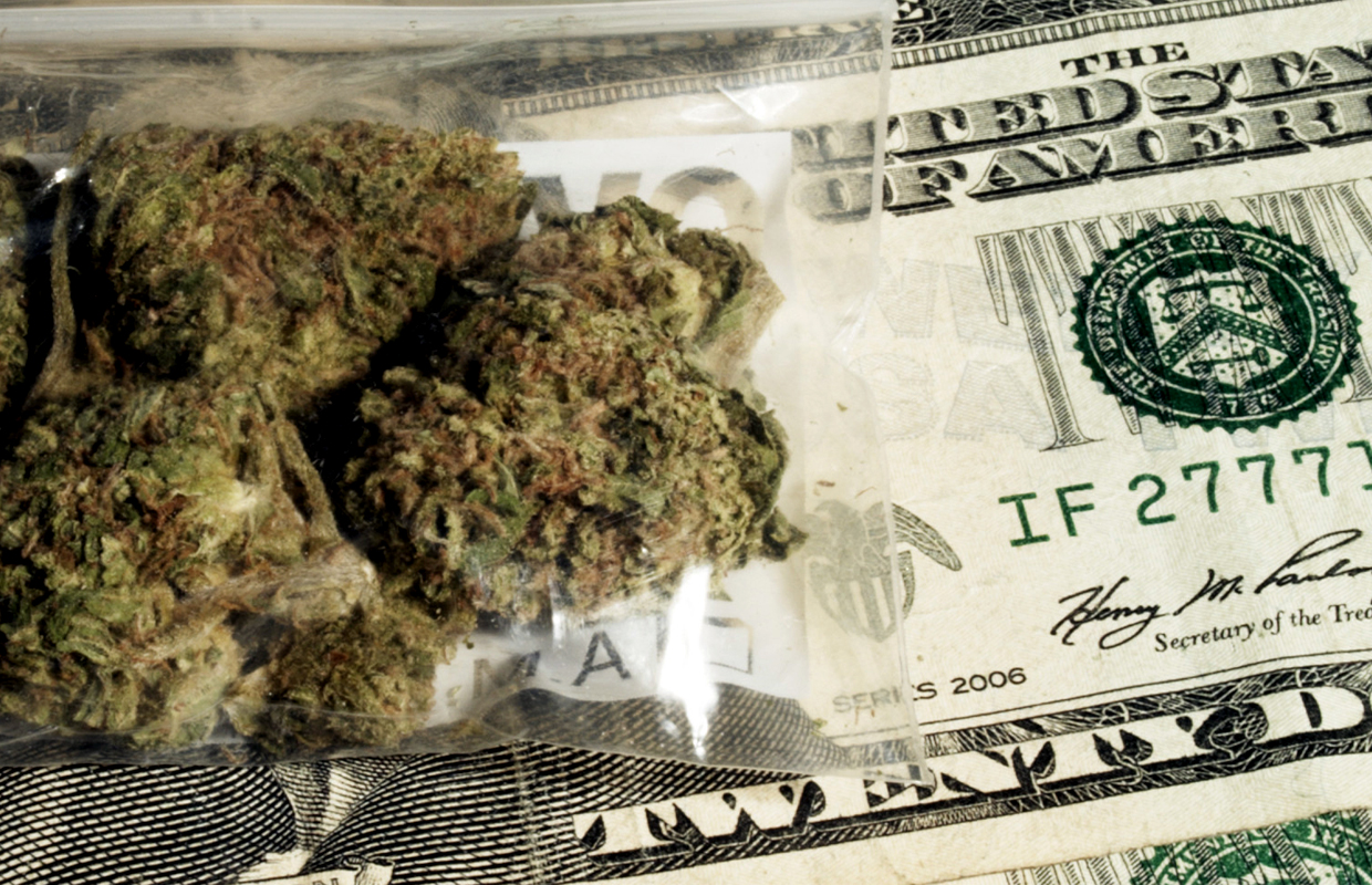 A five dollar bill is exchanged for a small bag of marijuana that has not been taxed due to an oversight in CO, resulting in less money for public schools.
