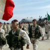 Italian soldiers wave an Italian flag on an airstrip.