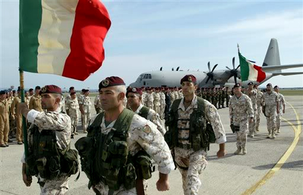 Italian soldiers wave an Italian flag on an airstrip.
