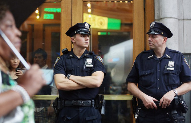 Two NYPD officers stand outside a door as they look to complete arressts other than "buy and bust" arressts.