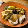 An orange plate holds typical Thanksgiving fare, alongside infused mashed potatoes and stuffing.