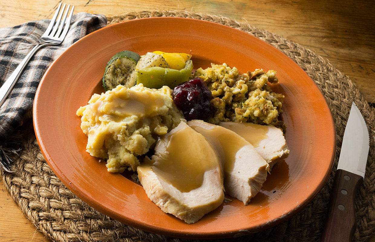 An orange plate holds typical Thanksgiving fare, alongside infused mashed potatoes and stuffing.
