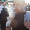 A man at a Cannabis Cup takes a hit from a huge joint.