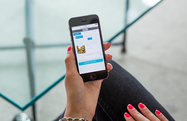 A woman hold out her phone as she accesses the Eaze app, the Uber of cannabis.