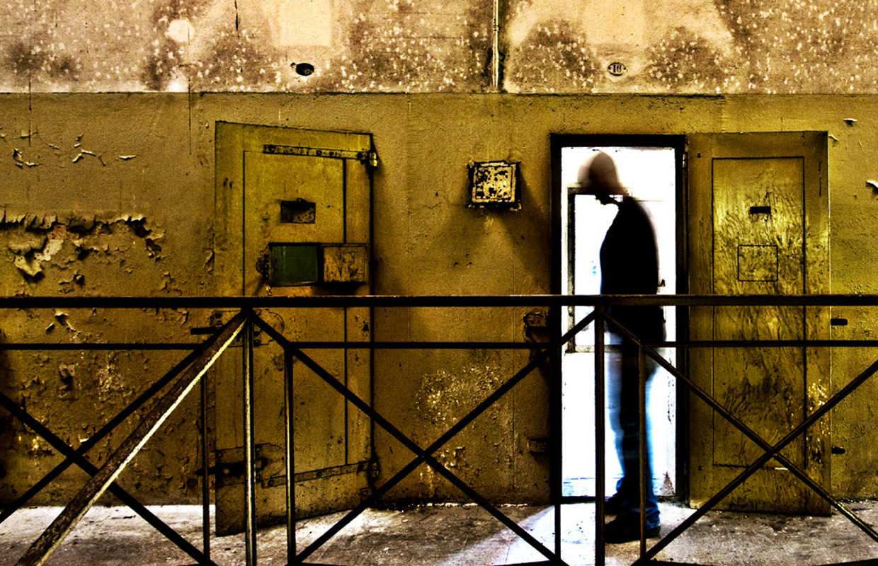 The shillouhette of a man stands in an abandoned prison, which he was just released from.