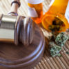In Rhode Island a gavel sits next to a prescription bottle spilled over with mmj as a student sues a company for discrimination as she uses mmj to treat her migraines.