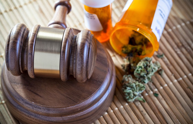 In Rhode Island a gavel sits next to a prescription bottle spilled over with mmj as a student sues a company for discrimination as she uses mmj to treat her migraines.