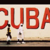 Two Cubans walk by a large sign that says "CUBA" as the U.S. tries to improve relations with Cuba.