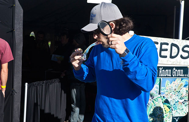 Man in Blue Shirt Uses Magnifying Glass to Light Bowl
