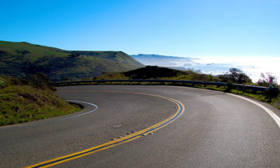 A Curve Bends in a Road With Blue Sky Background