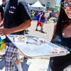 A woman in aviator sunglasses at the High Times Cannabis Cup holds a silver tray of edibles samples that have been properly dosed.