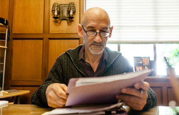 Dr. Lucido, wearing glasses, sits at his desk and reviews a patients file.